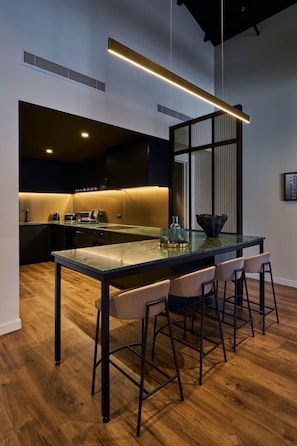 A modern kitchen with a central island, bar stools, and a pendant light. - The Grand Heritage Suite · 4 Bed · Entire Floor (Auckland City)