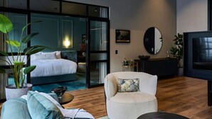 A modern hotel room with a bed, a seating area with a coffee table, a TV, and a large window. - The Grand Heritage Suite · 4 Bed · Entire Floor (Auckland City)