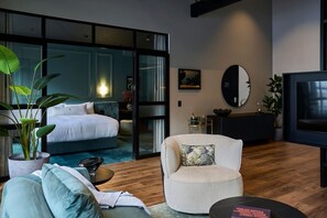 A modern hotel room with a bed, a seating area with a coffee table, a TV, and a large window. - The Grand Heritage Suite · 4 Bed · Entire Floor (Auckland City)