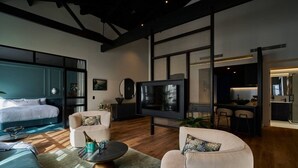 A modern living room with a large TV, a sofa, a coffee table, and a bed. - The Grand Heritage Suite · 4 Bed · Entire Floor (Auckland City)