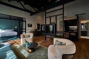 A modern living room with a large TV, a sofa, a coffee table, and a bed. - The Grand Heritage Suite · 4 Bed · Entire Floor (Auckland City)