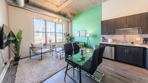 A modern kitchen with dark wood cabinets, a stainless steel dishwasher, and a large window overlooking a cityscape.