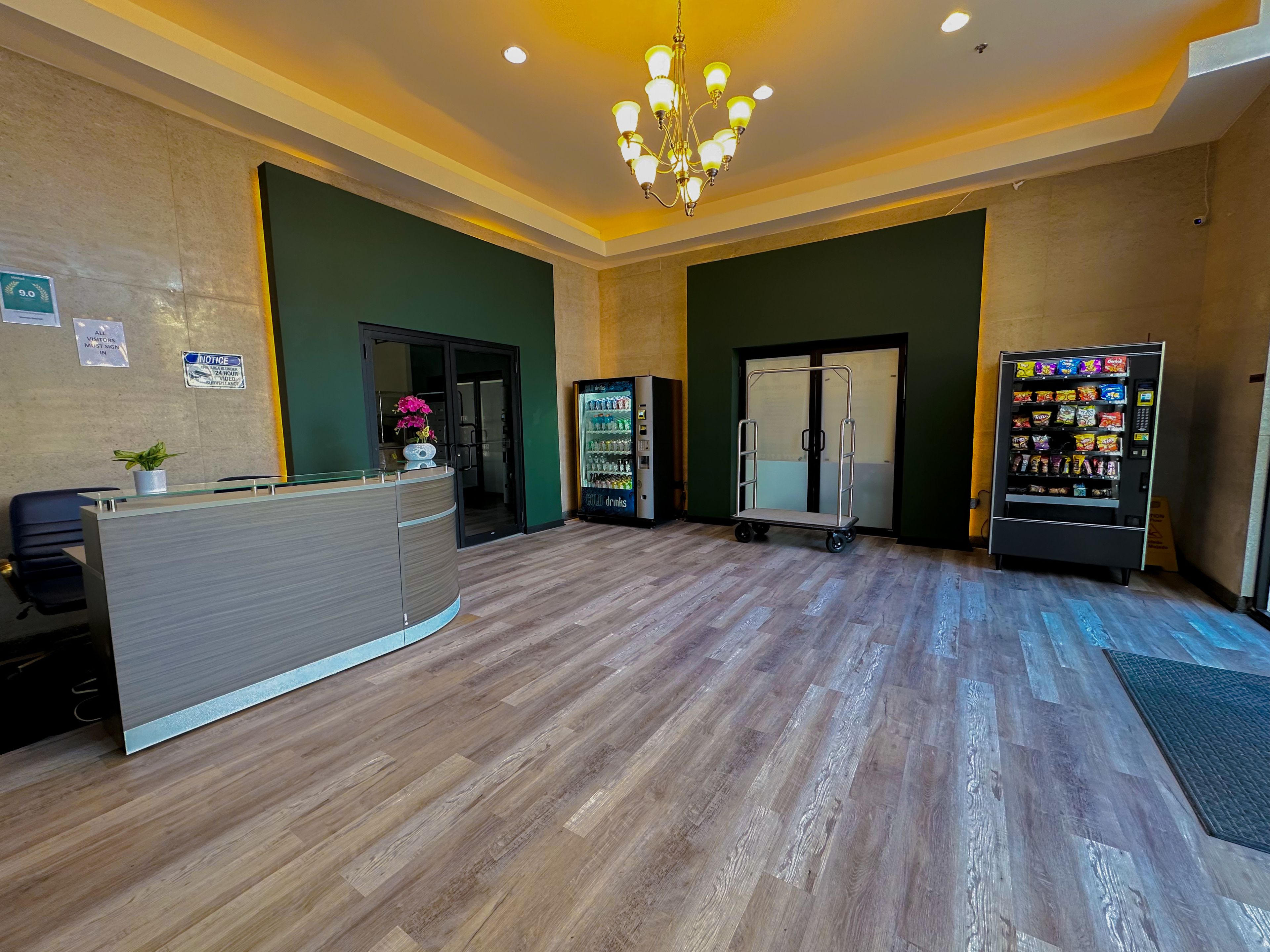 A reception area with a wooden floor, a reception desk, a vending machine, and a refrigerator.