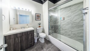 A modern bathroom with a vanity, toilet, and a glass-enclosed shower.