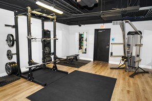 A gym with weightlifting equipment, a bench, and a door marked "EXIT".