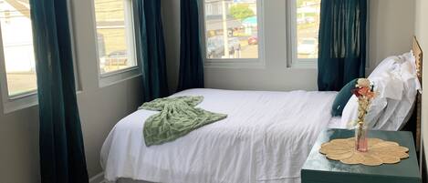 Un dormitorio con dos camas, una ventana, una mesita de noche con un florero y una mesita de noche verde.