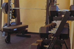Une salle de sport équipée de matériel de musculation, de bancs et d’un support à barres.