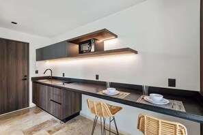 A modern kitchen with a dark wood cabinet, a built-in microwave, and a bar area with stools.