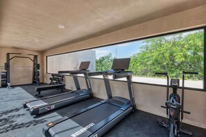 Une salle de sport équipée de tapis de course, d’un vélo d’appartement et de matériel de musculation.