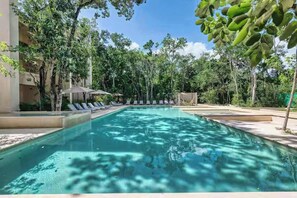 A swimming pool surrounded by trees and lounge chairs. - Chic Jungle 1BR: Balcony Priv Pool, Steam & Gym (Tulum)