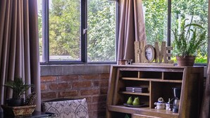 A rustic room with a brick wall, wooden furniture, a small refrigerator, and a window with curtains. - Natural refuge cabin in the Akron World Cup 2026 area (Jal.)