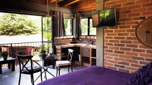 Una habitación con cama, una mesa de comedor, sillas, una zona de cocina y un televisor montado en la pared.