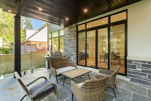 An outdoor patio with wicker furniture, a grill, and a stone wall.