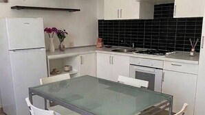 Eine kleine Küche mit weißen Schränken, einem Glastisch und vier Stühlen.