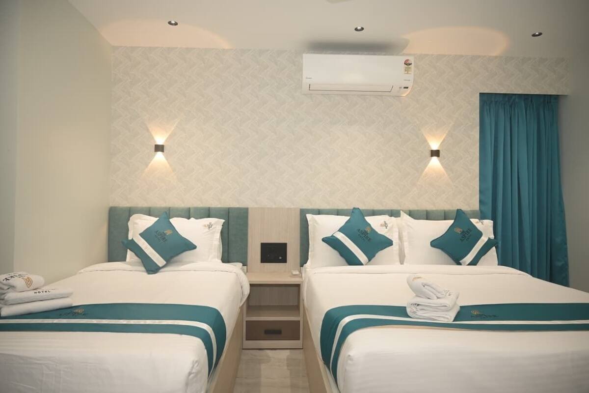 Ein Hotelzimmer mit zwei Betten, einer Wand-Klimaanlage und zwei Wandleuchten.