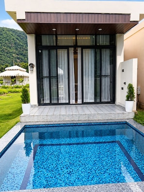A modern building with a swimming pool, large glass doors, and a view of a lush green landscape. - kaya nature resort (Thanagazi)