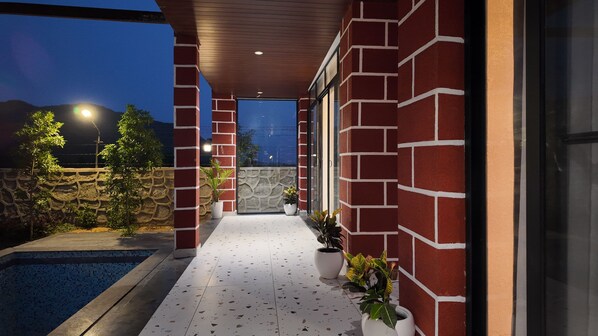 A covered outdoor area with a pool, red brick walls, and potted plants. - kaya nature resort (Thanagazi)