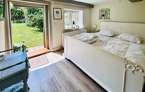 Une chambre à coucher avec un lit, une fenêtre, un radiateur et une porte donnant sur un jardin.