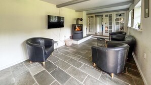 A living room with stone flooring, a fireplace, and black leather chairs. - 6 bedroom gorgeous home in Ribe (Ribe)