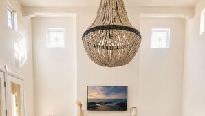Ett vardagsrum med en öppen spis, en stor kristallkrona, en soffa och ett soffbord.