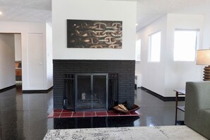 Un salón espacioso con chimenea, un cuadro abstracto de gran tamaño y un sofá moderno.