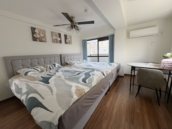 A bedroom with a bed, a desk, a chair, a ceiling fan, and artwork on the wall. - AVENIR STAY HANEDA (Haginaka)