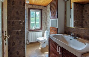 A bathroom with a window, a toilet, a sink, and wooden cabinetry. - 4 bedroom awesome home in Lönsboda (Lönsboda)