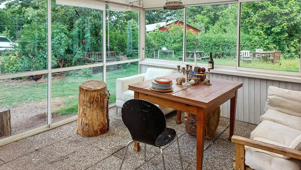 Une véranda avec une table, des chaises et une vue sur le jardin.
