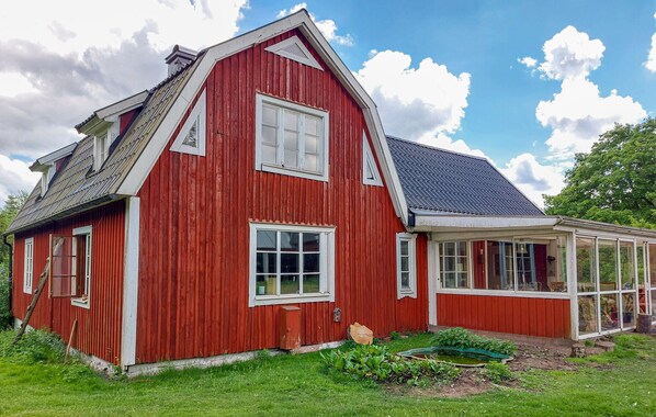 A red wooden house with a gabled roof and a glass conservatory. - 4 bedroom awesome home in Lönsboda (Lönsboda)