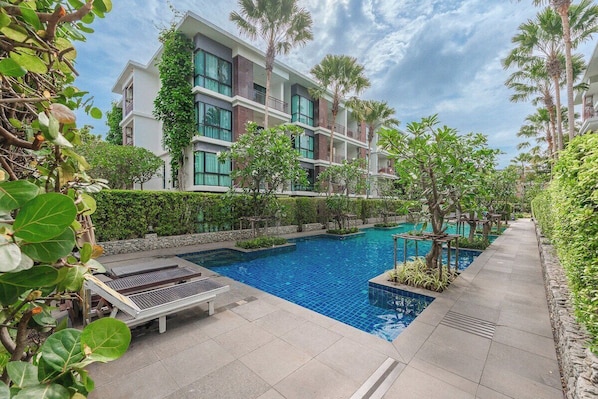 Un hôtel doté d’une piscine, de chaises longues et de palmiers.