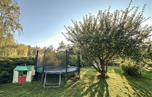 Ein Trampolin in einem Garten mit Baum und kleiner Gartenhütte.