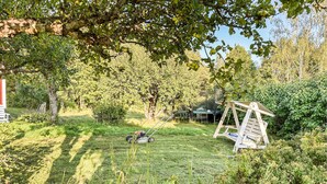 A grassy outdoor area with a swing set, a lawnmower, and a small shed. - Cozy home in Väddö with WiFi (Väddö)