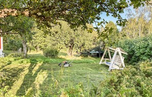 A grassy outdoor area with a swing set, a lawnmower, and a small shed. - Cozy home in Väddö with WiFi (Väddö)
