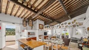 Zona d'estar àmplia amb taula de dinar, cadires, sofà i zona de cuina amb vistes.