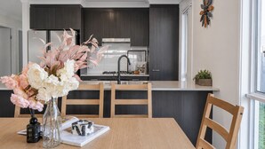 Una cocina moderna con armarios oscuros, un refrigerador de acero inoxidable, una estufa a gas y una ventana con vistas.