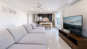 Una sala de estar moderna con un sofá, un comedor y un televisor.