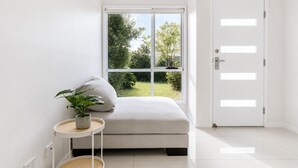 Habitación minimalista con ventana, puerta, una mesita con una planta y un sofá.