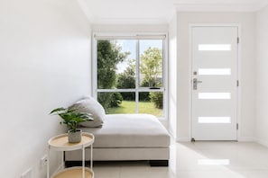 Habitación minimalista con ventana, puerta, una mesita con una planta y un sofá.
