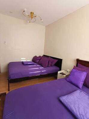 A bedroom with two beds, a nightstand, and a ceiling light fixture.