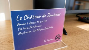 Placa para Le Chateau de Zambales, Fase 4 Bloco 11 Lote 10, indicando que se trata de uma Residência Sephora em Nagbunga, Castilla, Zambales. A placa também mostra o símbolo de proibido fumar.