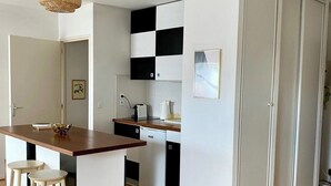 Une cuisine moderne avec un îlot central en bois, des armoires blanches et un dosseret à carreaux.