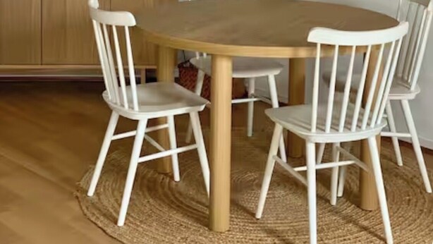 Un coin repas comprenant une table ronde en bois, des chaises blanches, un buffet en bois et deux miroirs décoratifs fixés au mur.