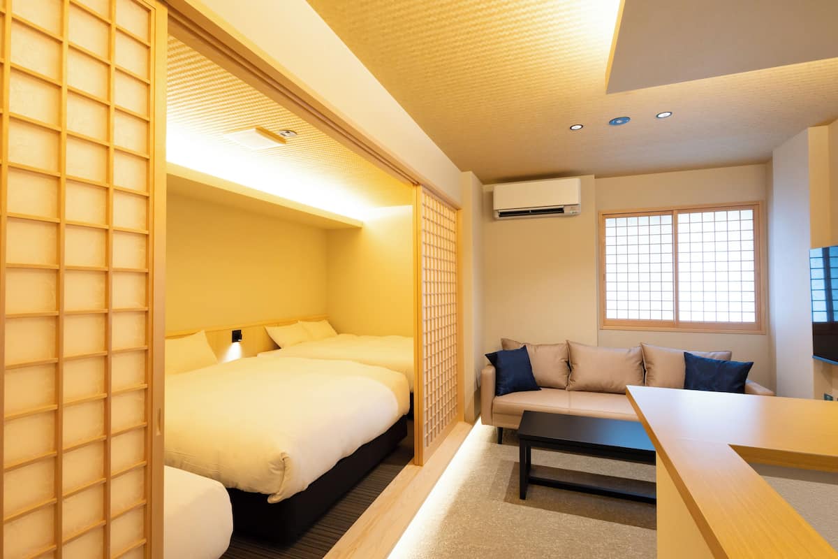 A hotel room with a bed, a sofa, a table, and a window.