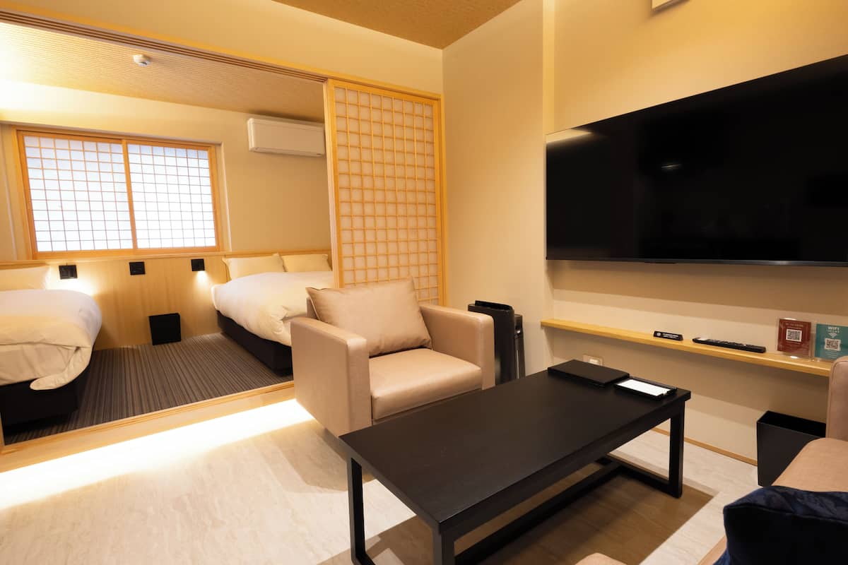 A hotel room with a bed, a sofa, a coffee table, a TV, and a sliding door.