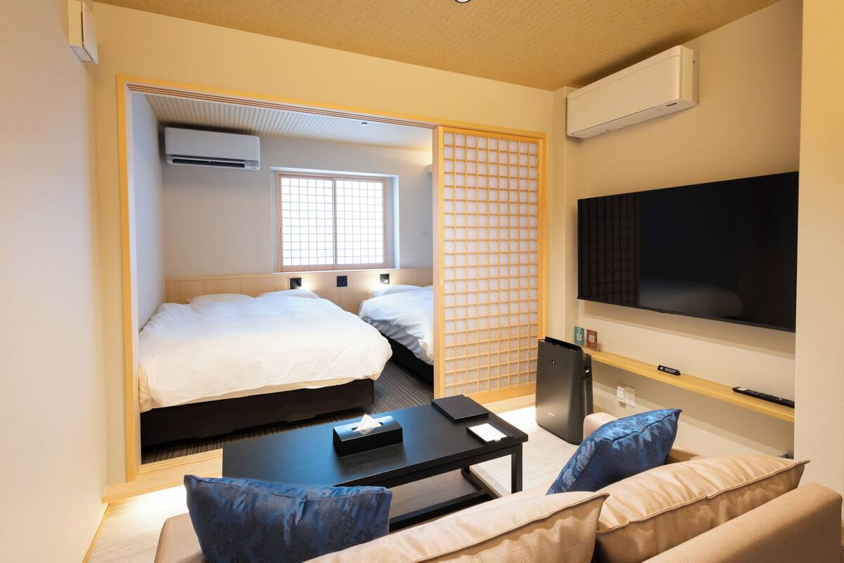 A hotel room with a bed, a TV, a coffee table, and a sofa.