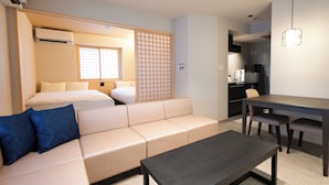 A hotel room with a bed, sofa, dining table, and kitchenette.