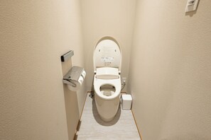 Ein kleines, schmales Badezimmer mit Toilette, Handtrockner und Mülleimer.