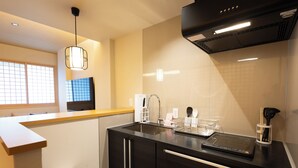 A modern kitchen with a black countertop, stainless steel appliances, and a window with grid blinds.