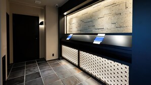 A reception area with a dark door, a wall-mounted information display, and patterned wall panels.