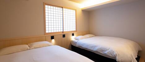 Une chambre d’hôtel avec deux lits, une fenêtre à carreaux et un appareil de climatisation.
